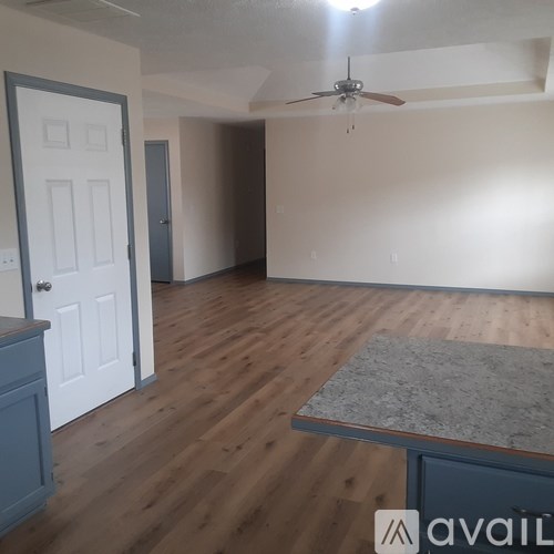 A room with a ceiling fan and a table with a granite top.