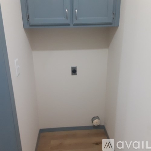 A small room with a light switch and a wooden floor.