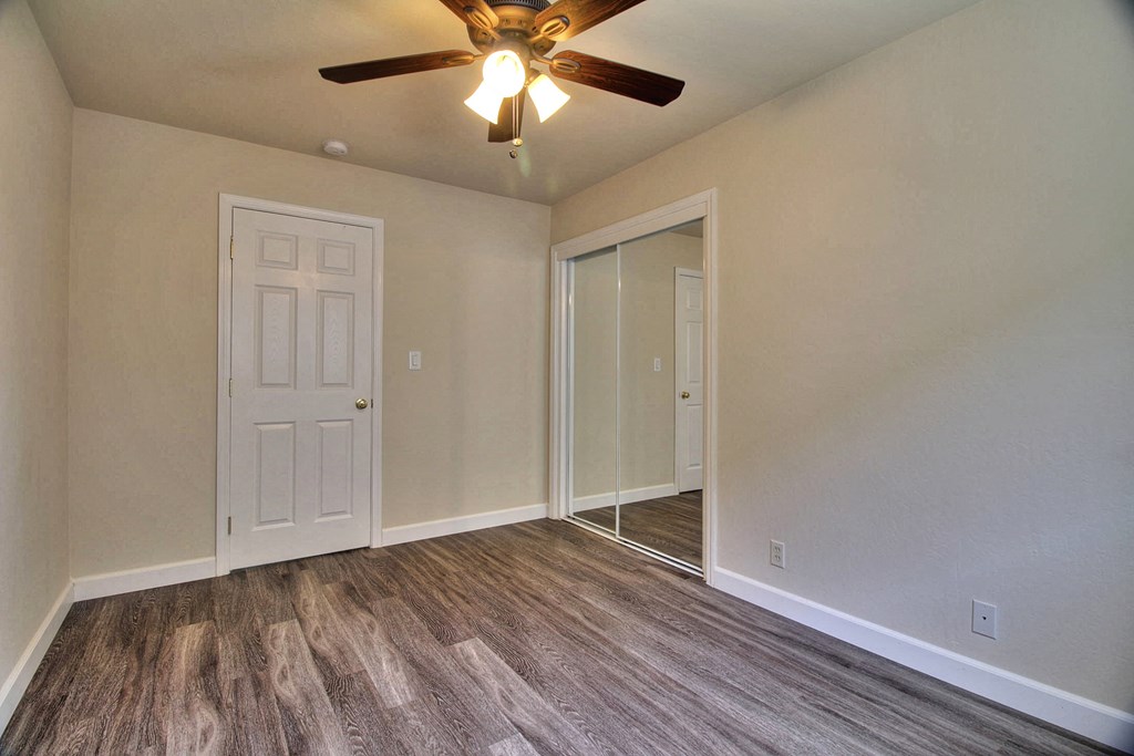 an empty living room with a ceiling fan and a door to a closet