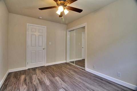 an empty living room with a ceiling fan and a door to a closet