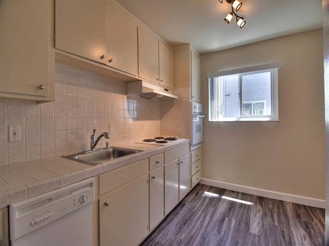 a kitchen with white cabinets and a sink and a window