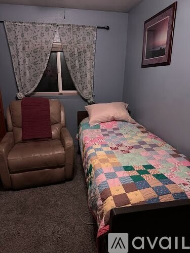 A bedroom with a bed, chair, and window.