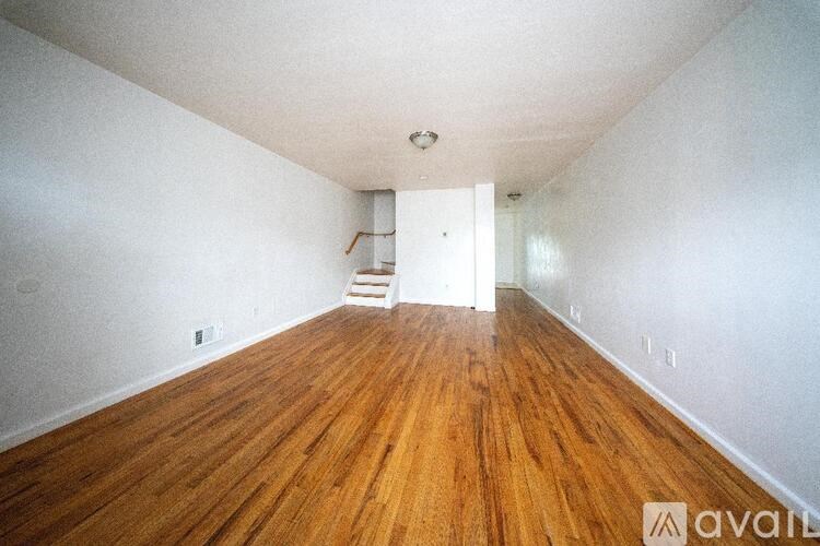 A room with wooden floors and a white wall with a doorway.