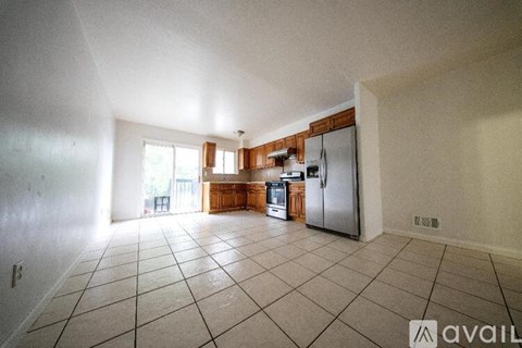A kitchen with a refrigerator, sink, and cabinets.