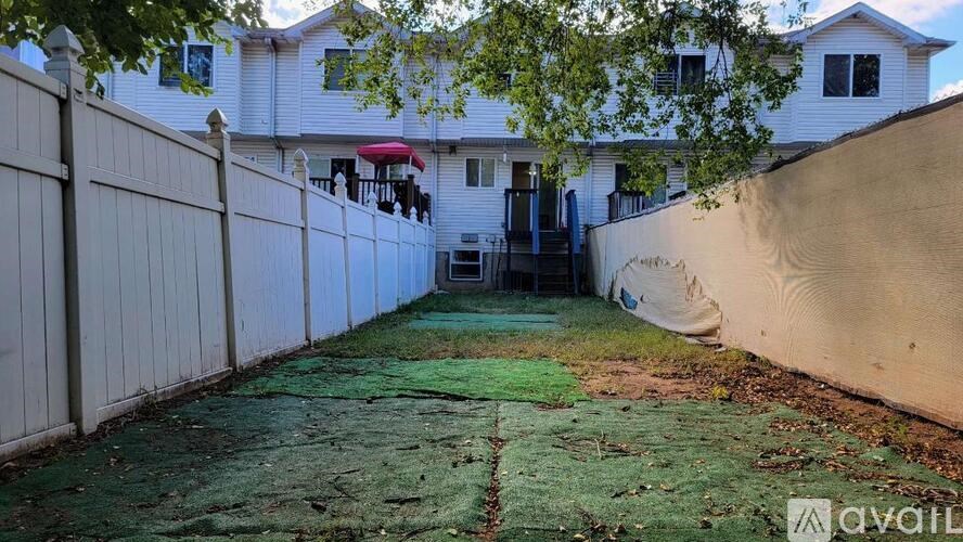 A backyard with a fence and a covered patio.