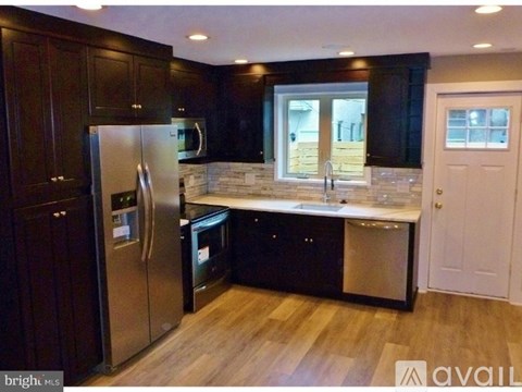 A kitchen with dark wood cabinets and a stainless steel refrigerator.