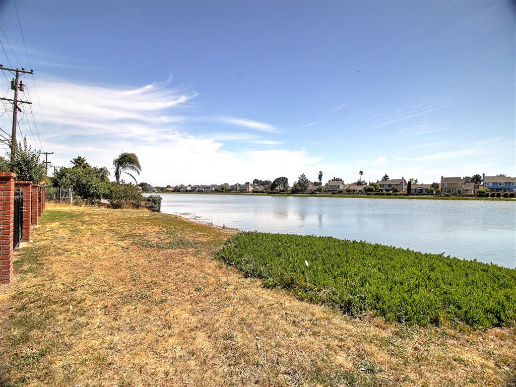 a body of water next to a grass field