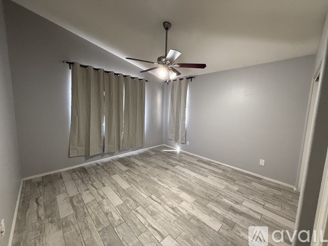 A room with a ceiling fan and a window with curtains.
