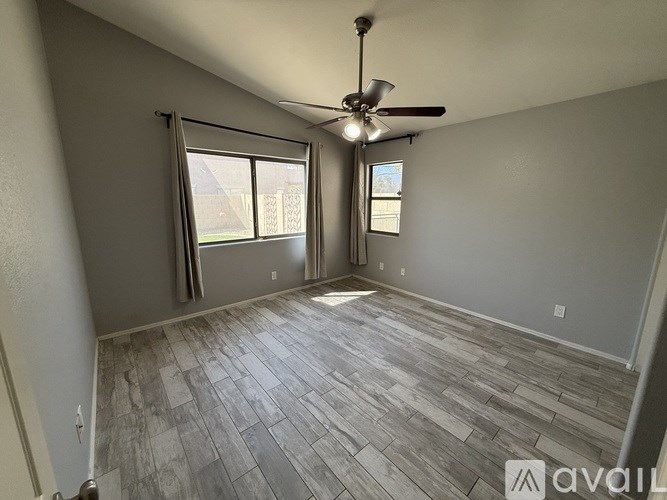 A room with a ceiling fan and sliding glass doors.