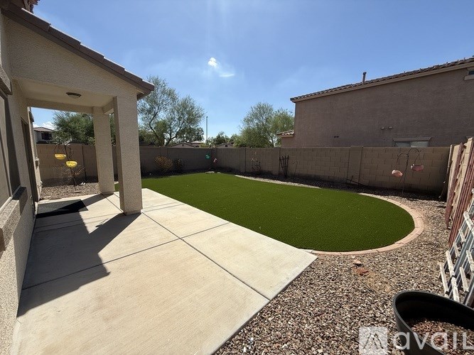A backyard with a green lawn and a concrete patio.