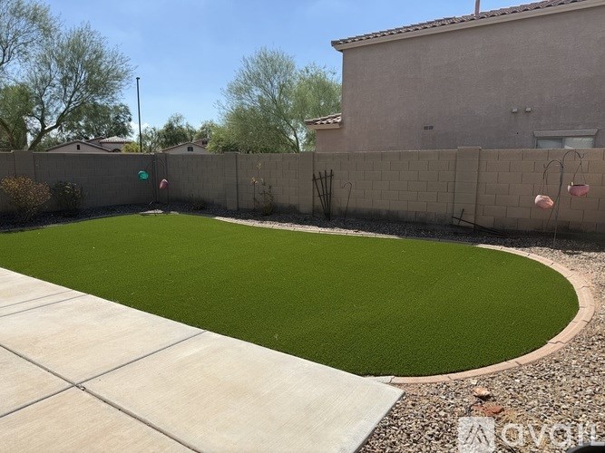 A backyard with a green lawn and a concrete patio.