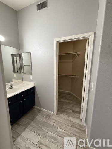 A bathroom with a sink, mirror, and a wooden floor.