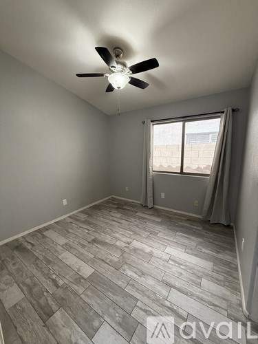 A room with a ceiling fan and a window with curtains.
