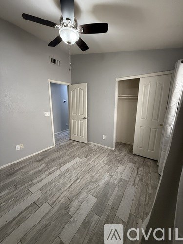 A room with a ceiling fan and wood flooring.