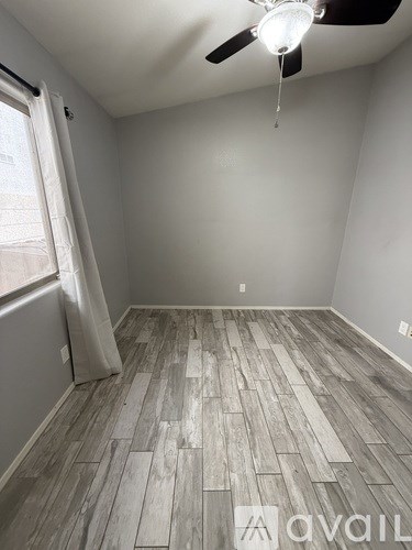A room with a ceiling fan and wooden flooring.
