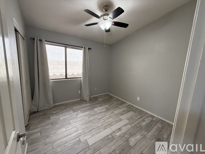 A room with a ceiling fan and a window with curtains.