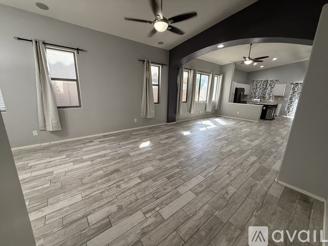 A spacious room with a wooden floor and a ceiling fan.