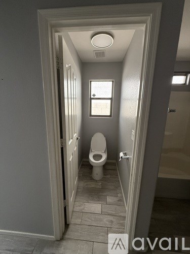 A bathroom with a toilet and a window.