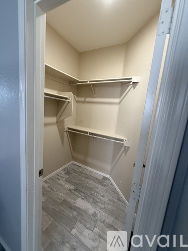 A small walk-in closet with shelves and a grey floor.