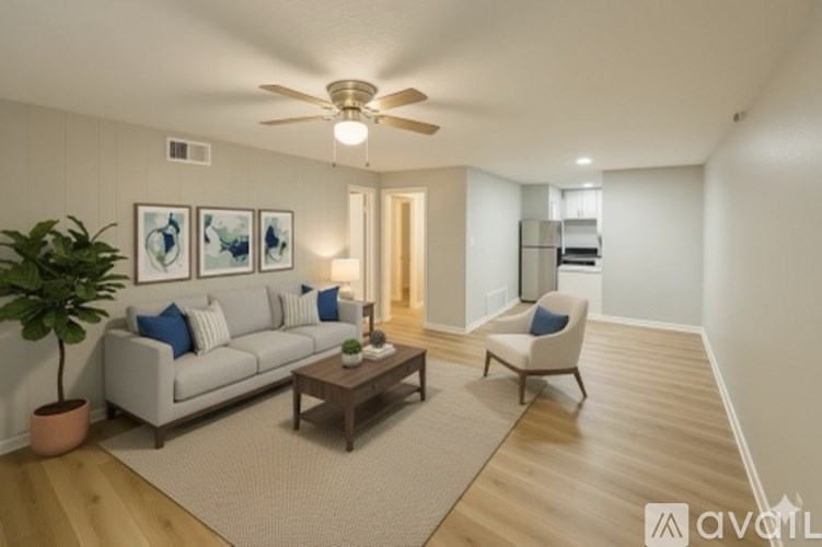 A living room with a couch, chair, and potted plant.