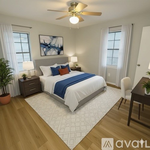 A bedroom with a bed, a ceiling fan, and a painting on the wall.