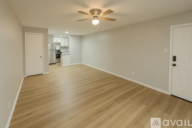 A spacious room with wooden flooring and a ceiling fan.