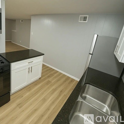 A kitchen with white cabinets and a black countertop.
