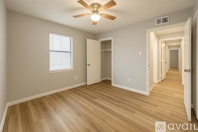 A room with a ceiling fan and wooden flooring.