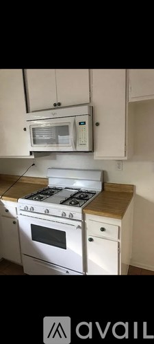 A kitchen with a white stove top oven and a white microwave above it.
