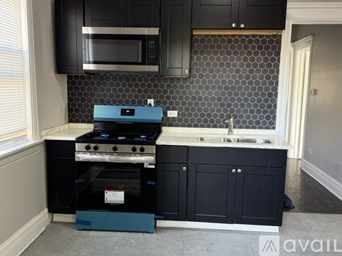 A kitchen with black cabinets and a blue stove top oven.