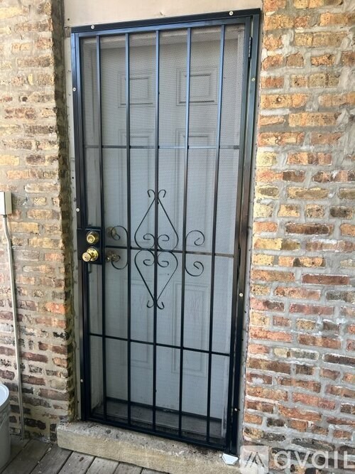 A black metal gate with a decorative design is set in a brick wall.