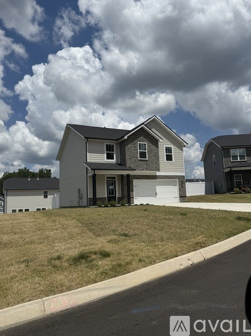 A house with a grey roof and white walls is in front of a cloudy sky.