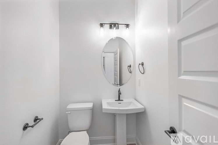 A white bathroom with a toilet, sink, and mirror.