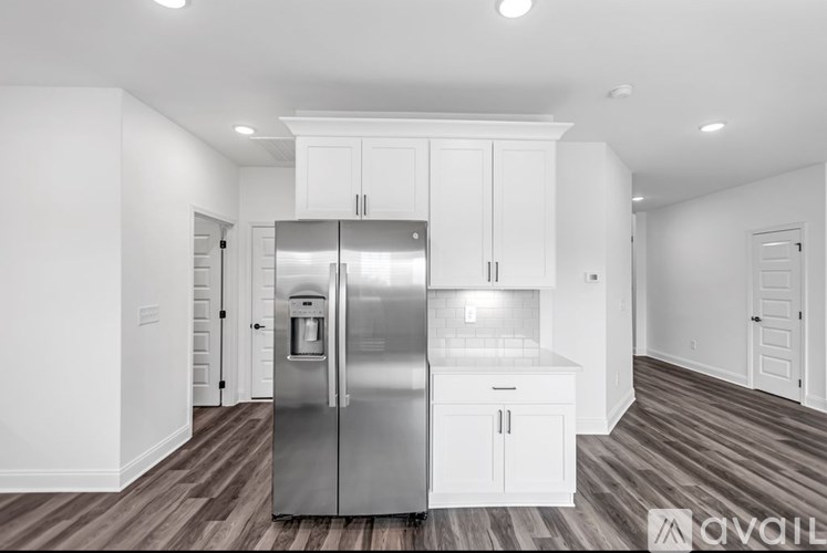 A modern kitchen with a stainless steel refrigerator and white cabinets.