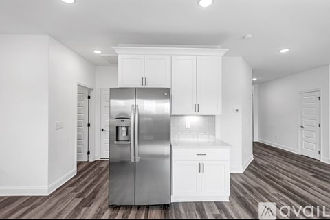 A modern kitchen with a stainless steel refrigerator and white cabinets.