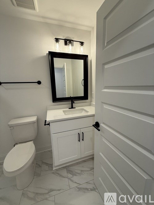 A bathroom with a toilet, sink, and mirror.