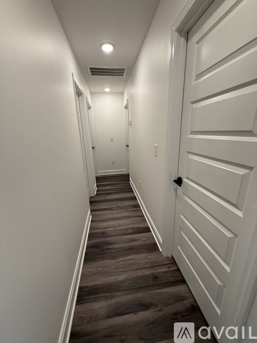 A long hallway with a white door on the right.