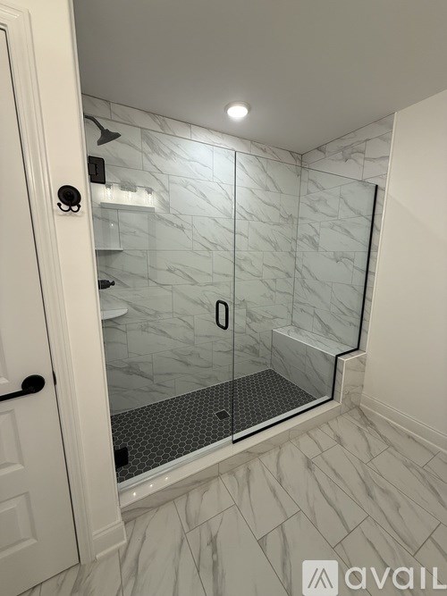 A bathroom with a walk-in shower and a white door.