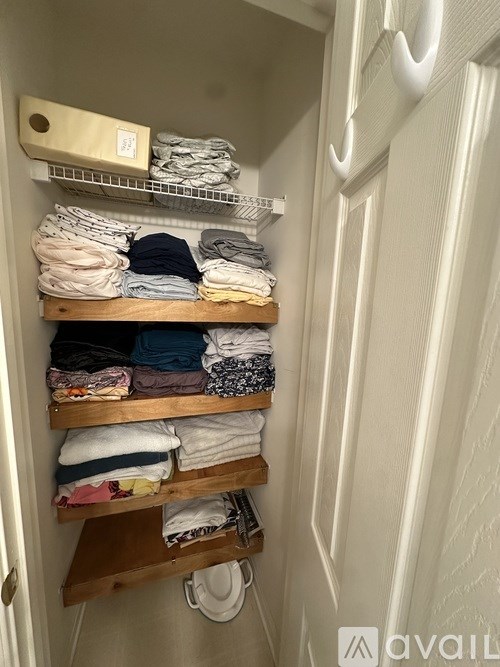 A white door with a shelf of folded clothes on it.