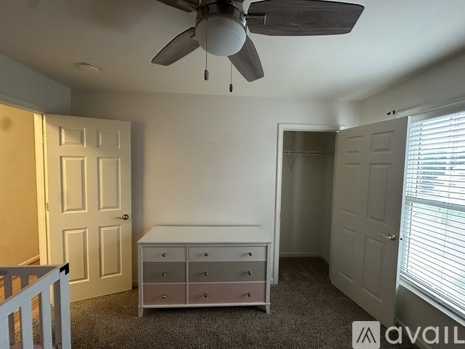 A room with a ceiling fan, a dresser, and a door.