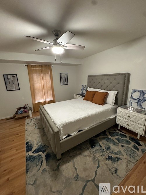 A bedroom with a large bed, a ceiling fan, and a rug on the floor.
