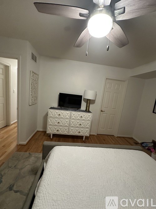 A bedroom with a bed, dresser, and ceiling fan.