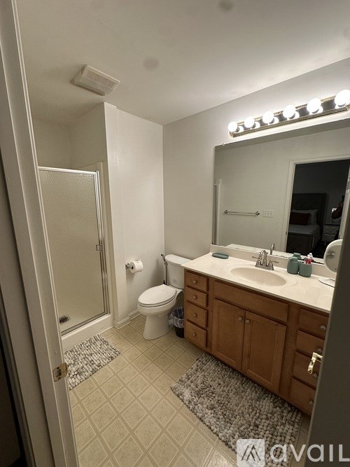 A bathroom with a toilet, sink, mirror, and a shower.