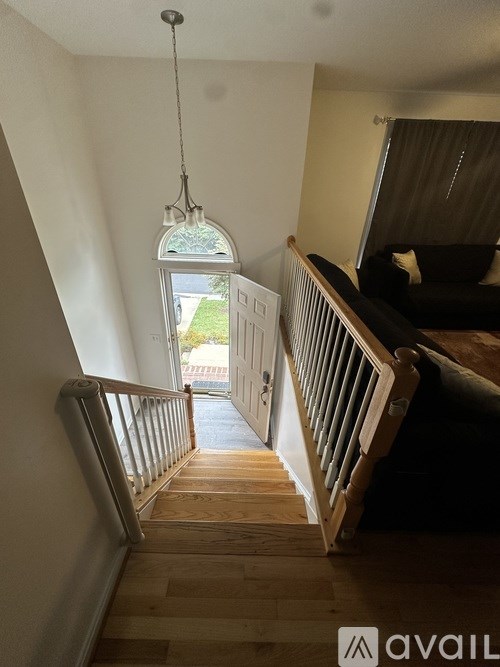 A staircase with a wooden handrail and a hanging light fixture.