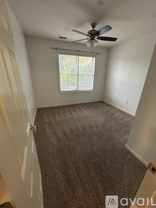 A room with a ceiling fan and carpeted floor.