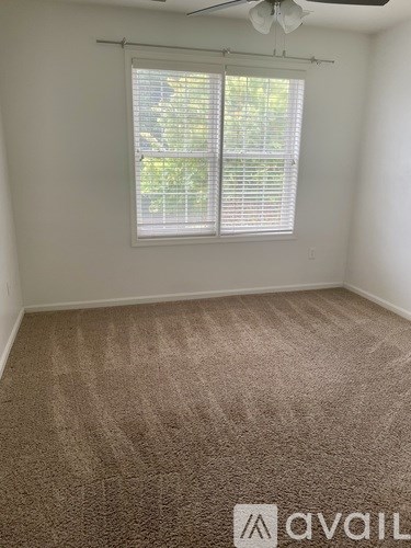 A room with a carpeted floor and a window with blinds.