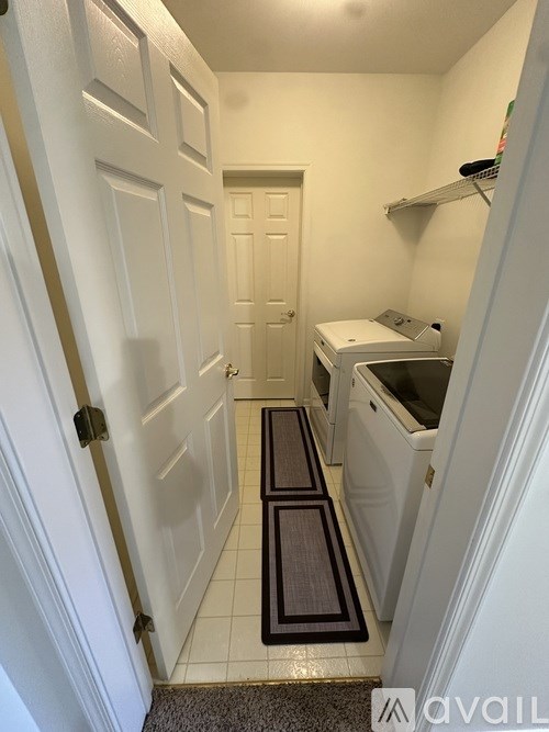 A hallway with a door on the left and a kitchen area on the right.
