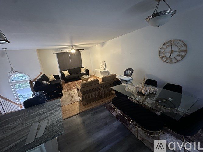 A living room with a glass table and a clock on the wall.
