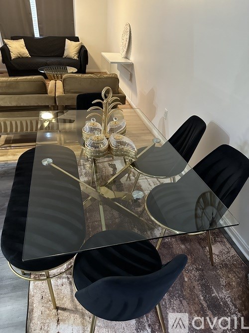 A glass dining table with four chairs and a decorative centerpiece.