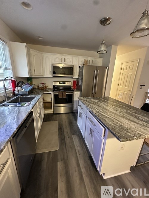 A kitchen with white cabinets and a marble countertop.